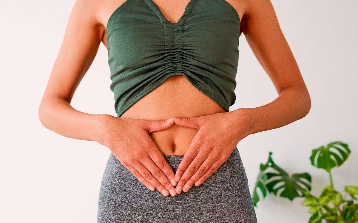 Frau in sportlichem Outfit hält entspannt ihren Bauch mit beiden Händen