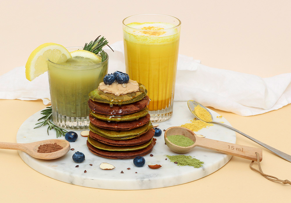 2 verschiedene InnoNature Lattes zubereitet mit selbstgemachten Pancakes auf einem marmorierten Präsentierteller