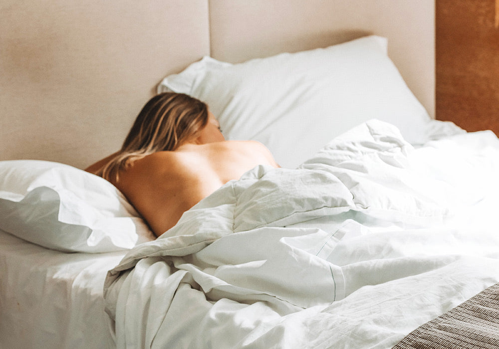 Rücken einer Frau, die im Bett liegt.