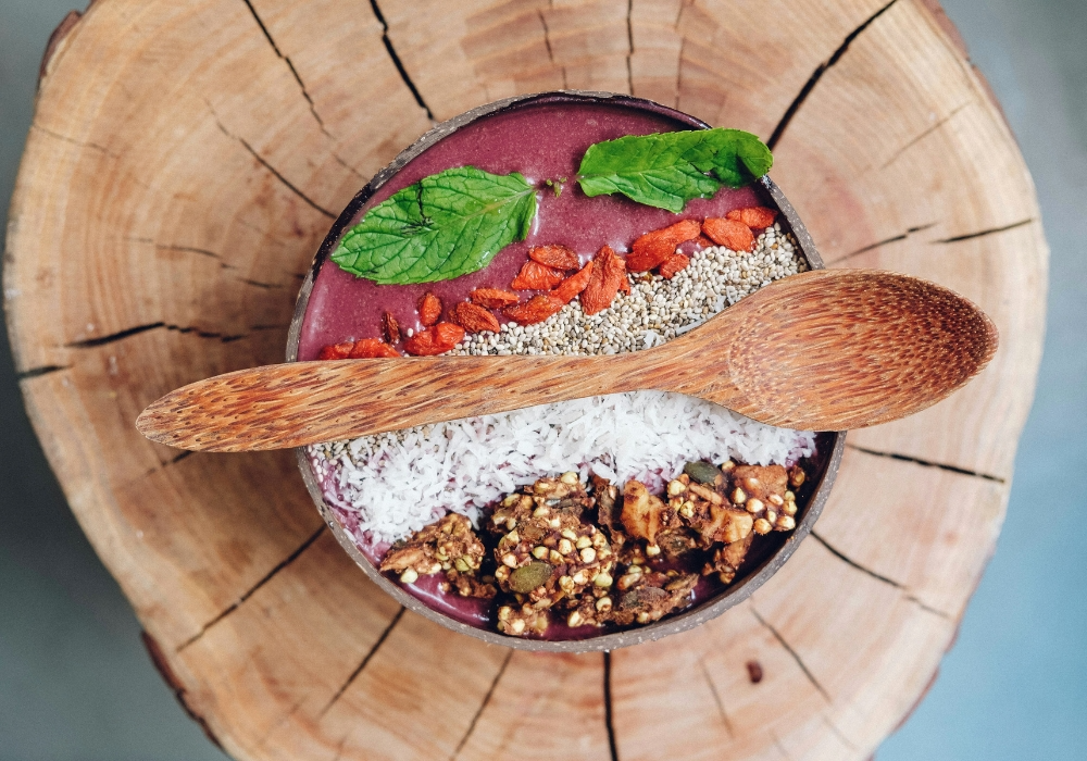 Acai Superfood Bowl mit Nüssen und Kokosraspeln in Holzschüssel