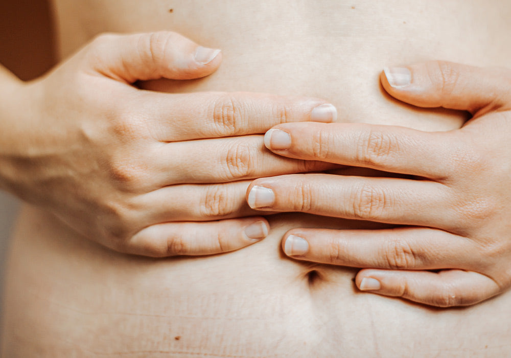 Person drückt Hände auf ihren Unterbauch.