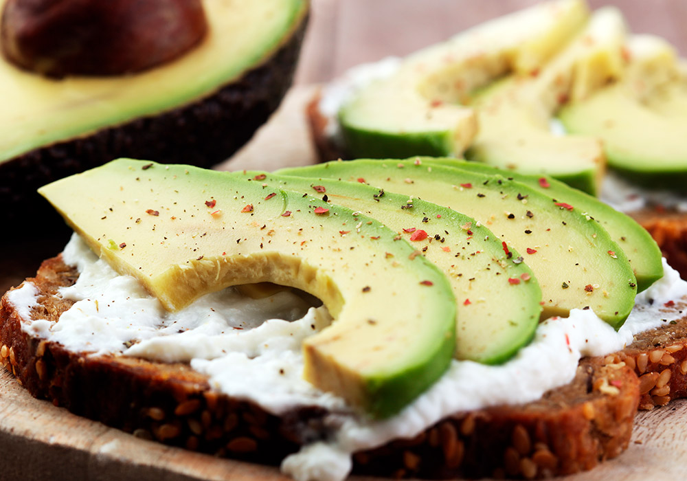 Eine Scheibe Brot mit Frischkäse und Avocado.