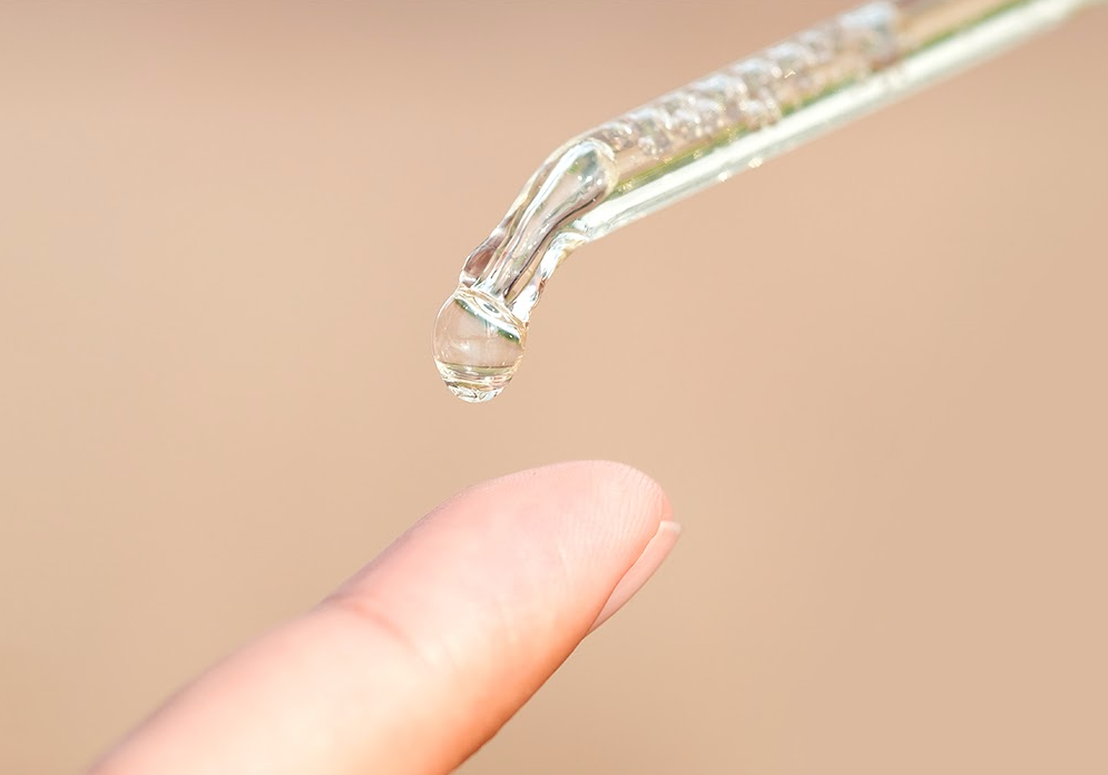 Hautöl tropft auf einen Finger