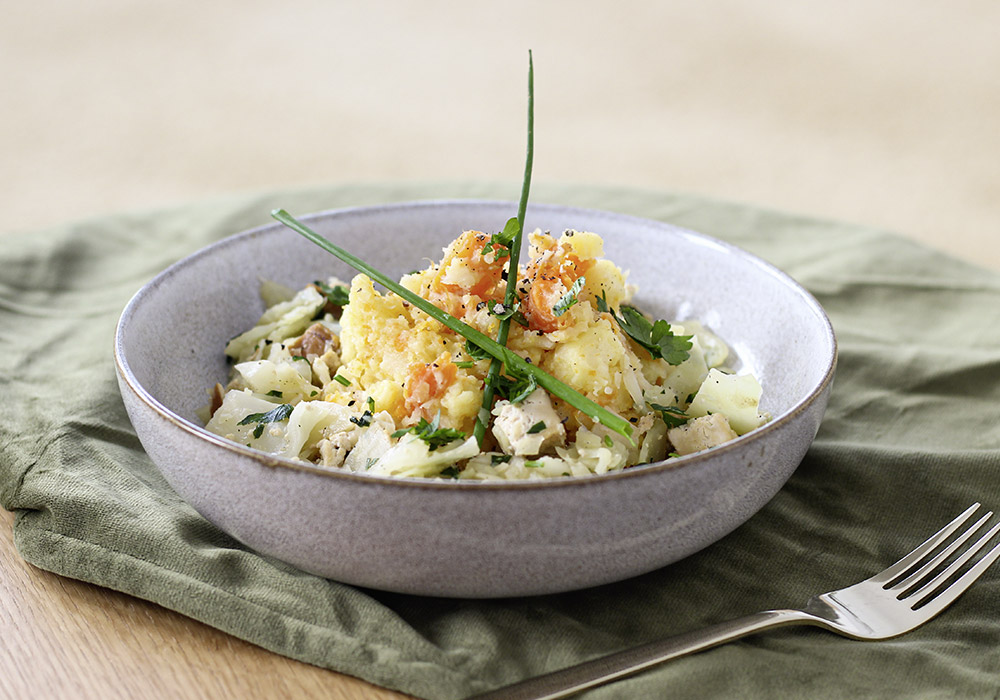 Weißkohl-Räuchertofu mit Möhren-Pastinaken Stampf in einer Porzellanschüssel. Drumherum liegt ein grünes Tuch und eine Gabel. 