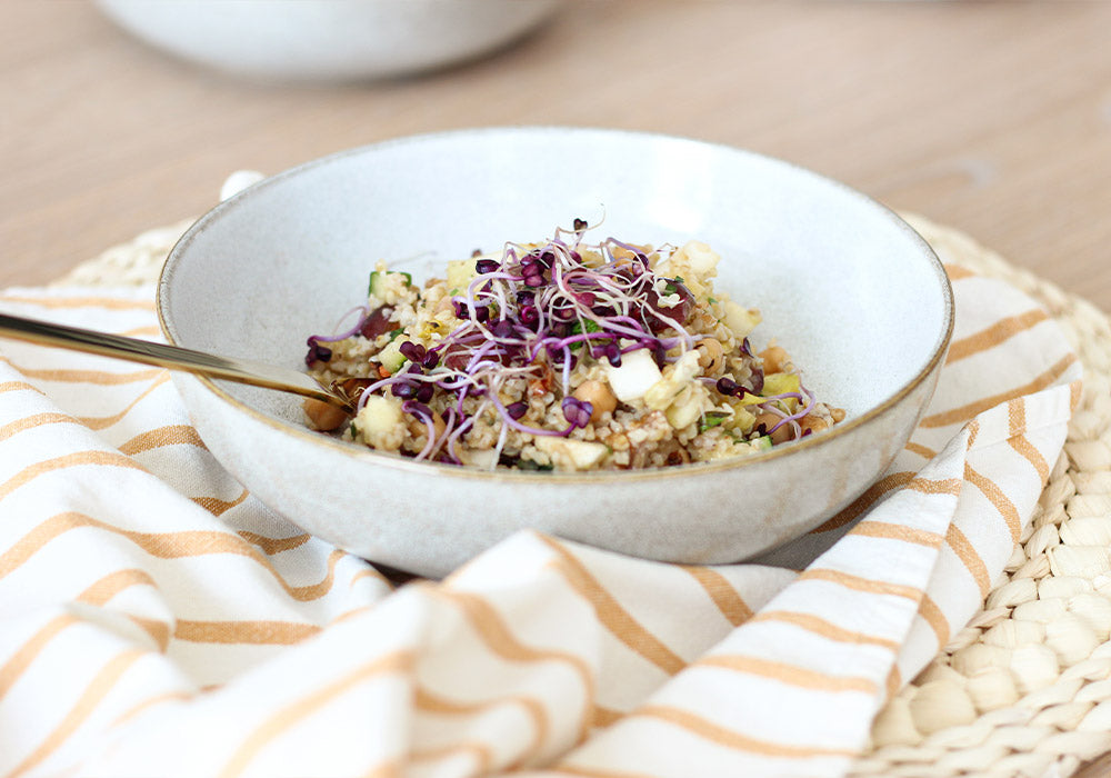 Bulgur-Kichererbsensalat mit Weintrauben in einer grauen Porzellanschüssel. 