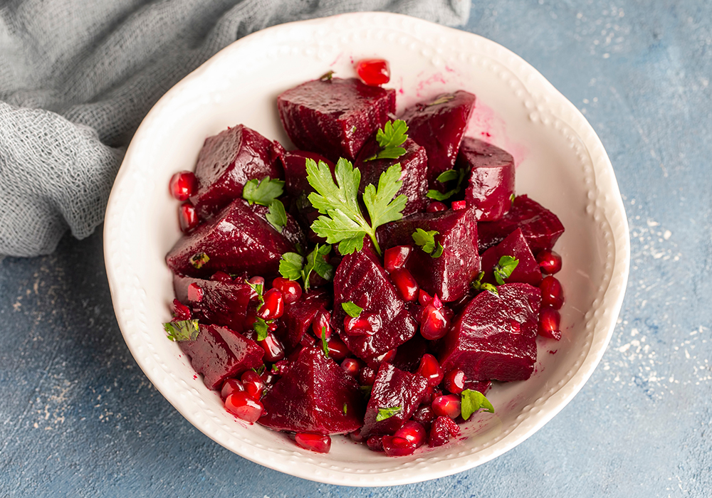 Rote Beete und Granatapfel in einer Schüssel mit grünen Gewürzen