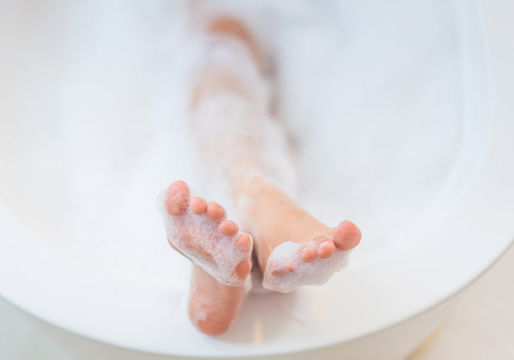 Füße einer badenen Person mit Schaum