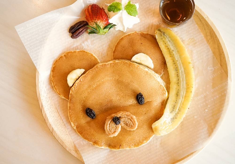Pancakes zu einem Mäusegesicht geformt mit Nüssen und Beeren