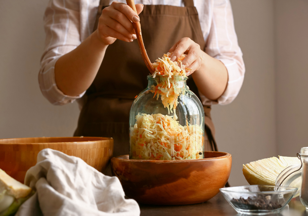 Person füllt Sauerkraut in ein großes Glas