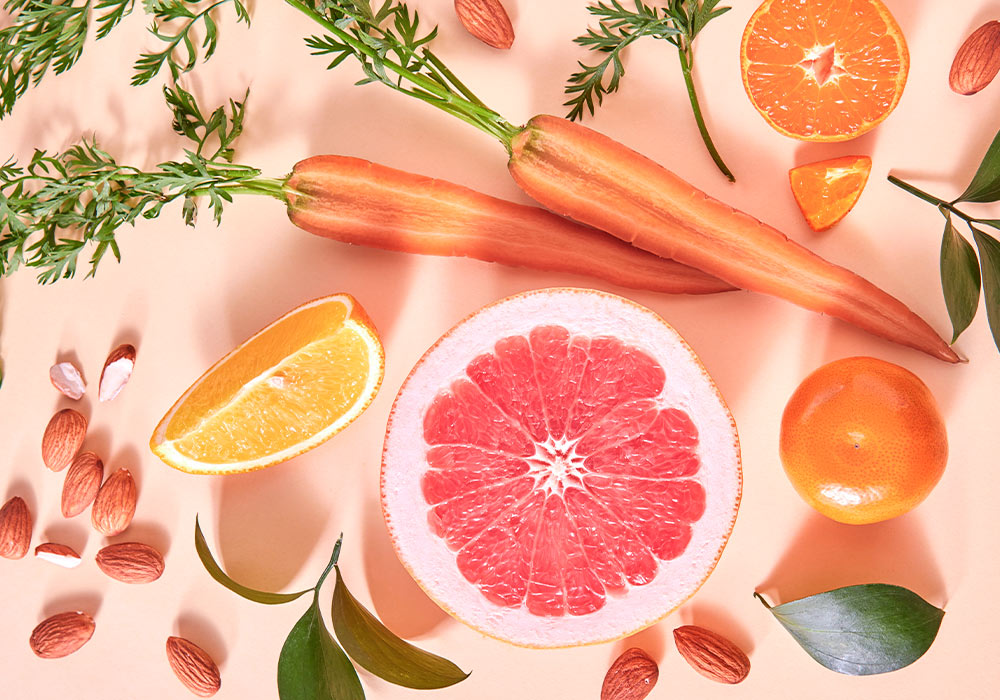 unterschiedliche, aufgeschnittene Obst- und Gemüsesorten auf einem leicht rosa Untergrund.
