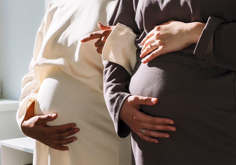 Zwei schwangere Frauen, die sich den Bauch halten. 