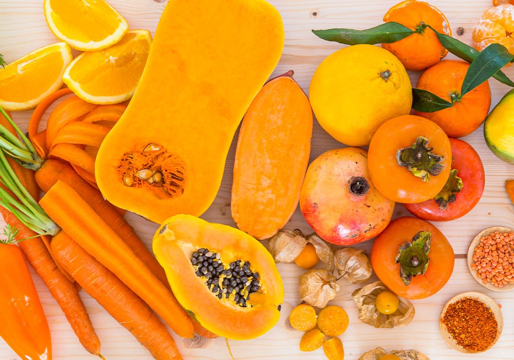 Orangefarbene Obst- und Gemüsesorten liegen auf einem Tisch.