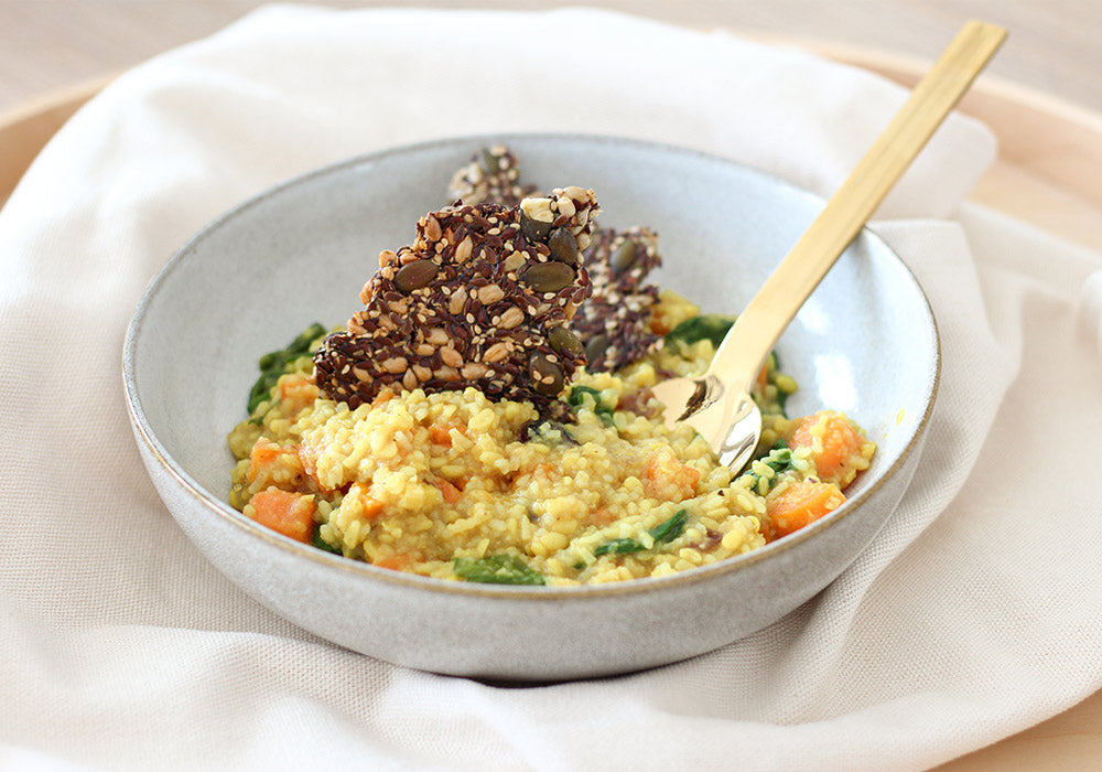Eine graue Schale gefüllt mit Kitchari aus Mung Dal, Basmatireis, Süßkartoffel und Karotte.  