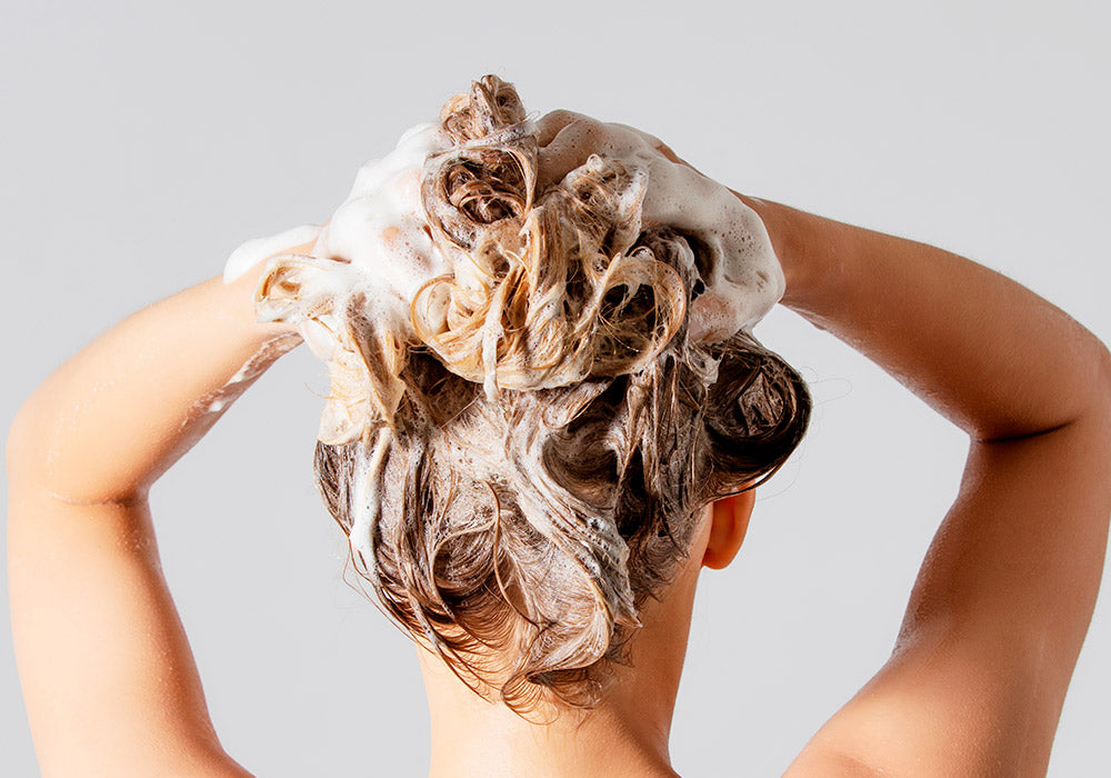 Hinterkopf einer Frau, die sich die Haare wäscht.