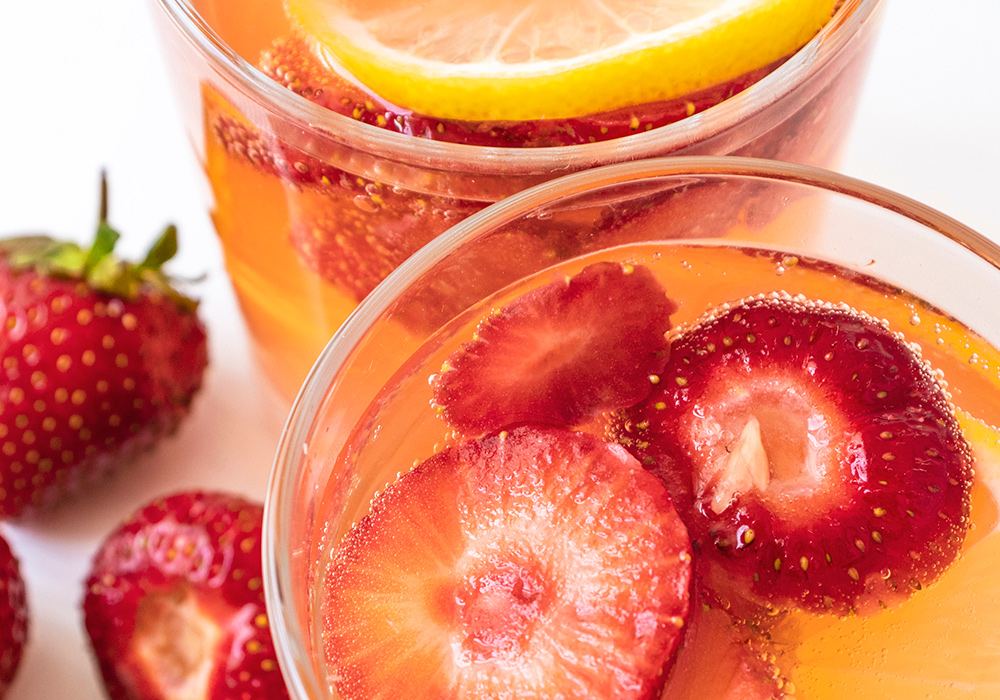 zwei Gläser mit gelblich-roter Flüssigkeit und Erdbeeren