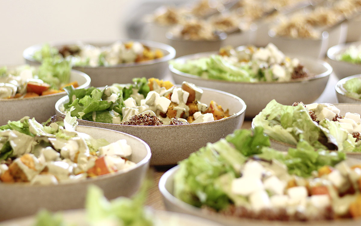 Mehrere Porzellanschüsseln gefüllt mit Ofengemüse, veganen Feta und Quinoa