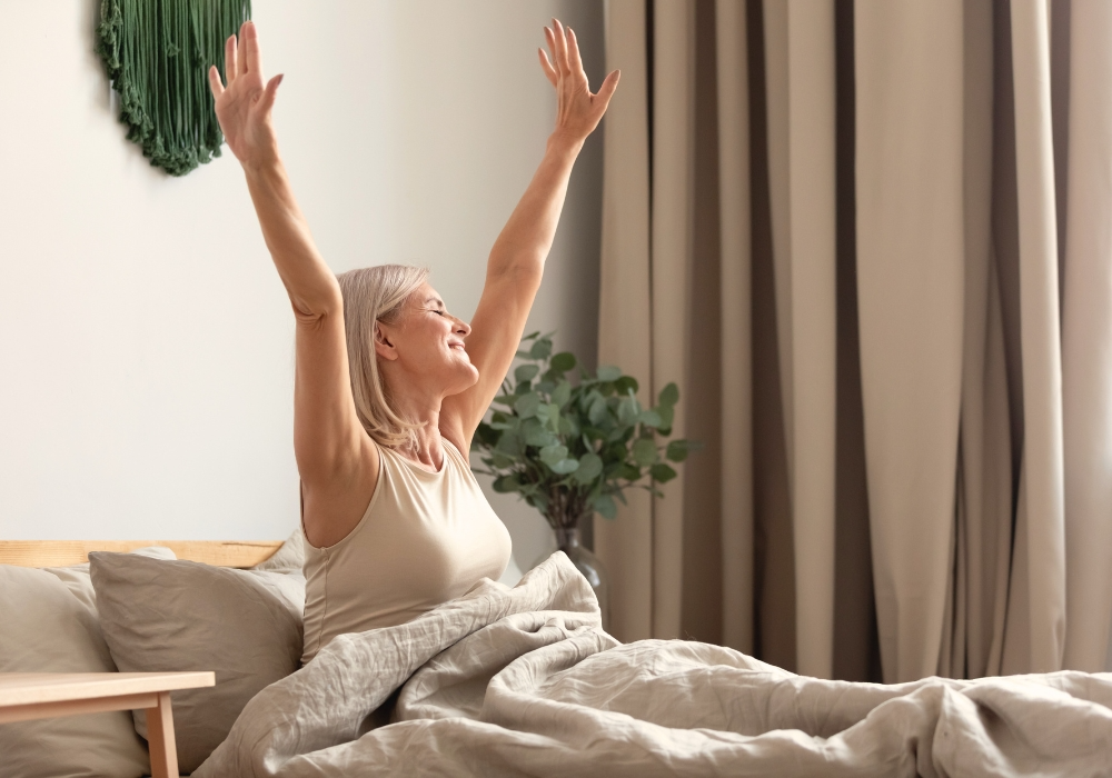 Person streckt sich morgens im Bett nach dem Aufwachen
