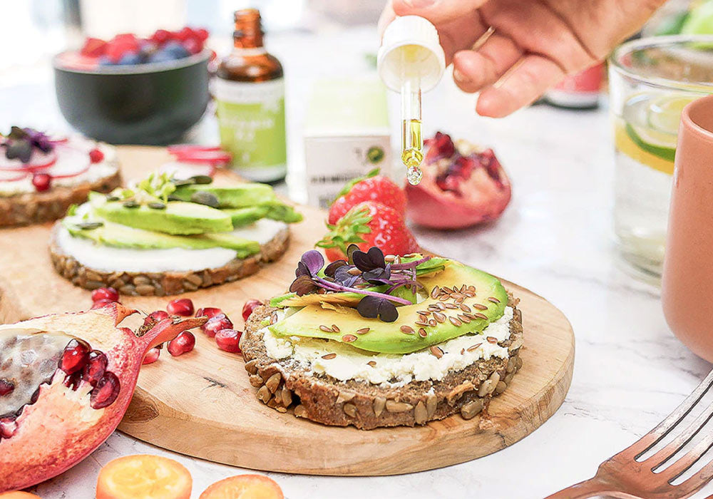 Auf einem Teller liegt eine Reiswaffel mit Avocado und Erdbeere, auf die Vitamin K2 draufgegeben wird.