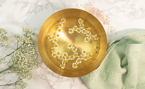 Badezusatz in goldene Schale mit Kamille für den Säure Basen Haushalt
