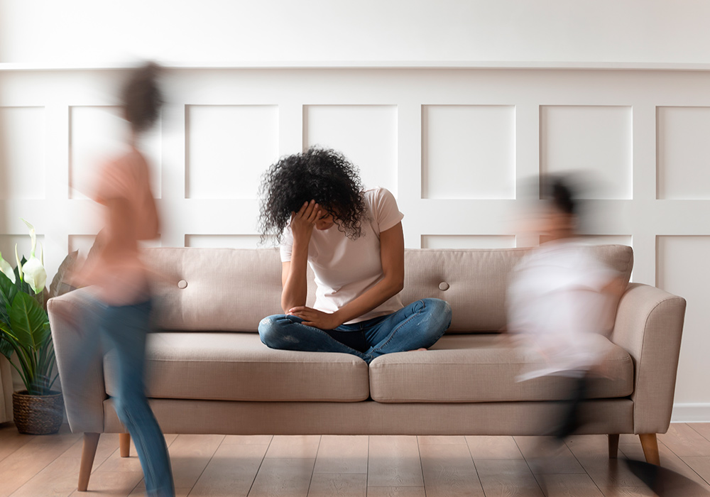 Frau in Stresssituation auf der Couch, Kopf in der Hand abstützend