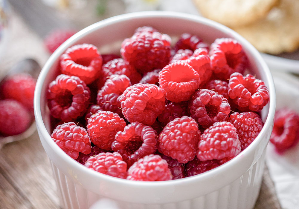 Kleines, weißes Schälchen mit frischen Himbeeren.