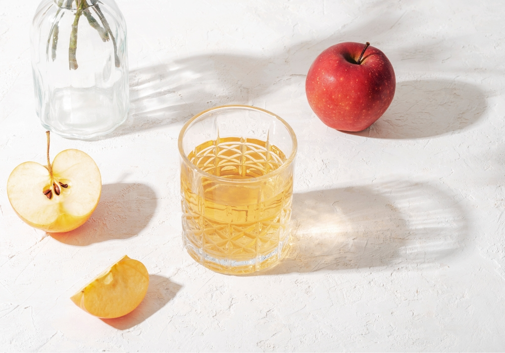 Frische Äpfel und Apfelessig in einem Glas mit Wasser verdünnt
