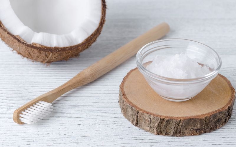 Kokosöl und eine Zahnbürstr auf dem Tisch zum ayurvedischen Öl ziehen am Morgen