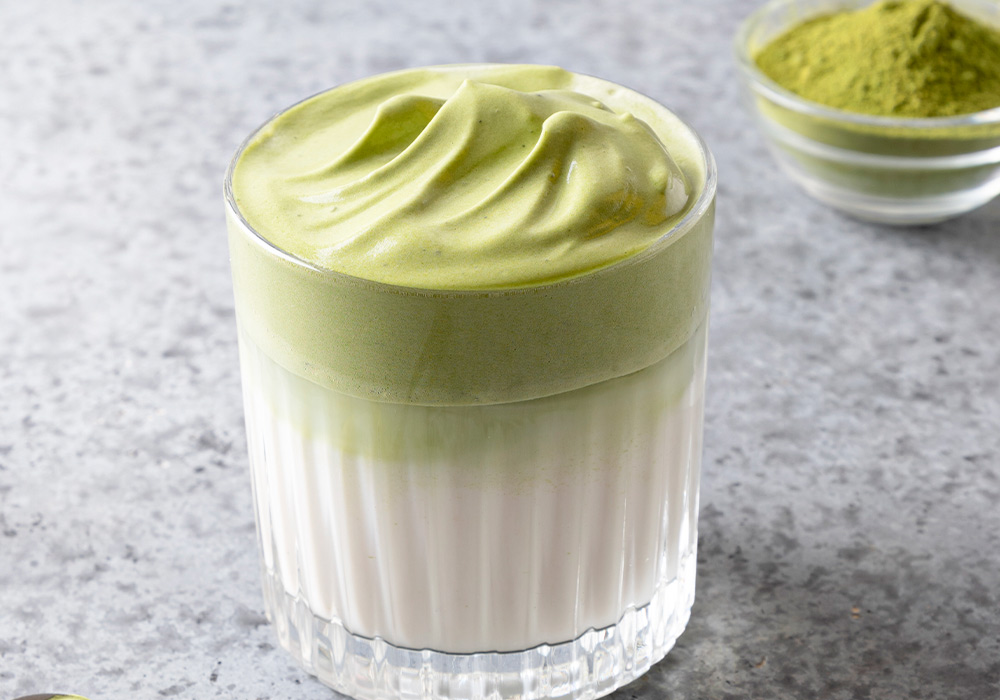 Glas mit aufgeschäumten Matcha Latte.