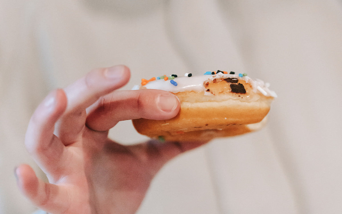 Frau hält einen Donut in der Hand.