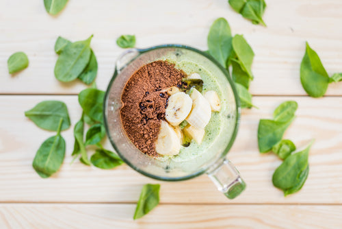 Mixer mit Smoothie-Zutaten von oben mit Basilikum-Blättern