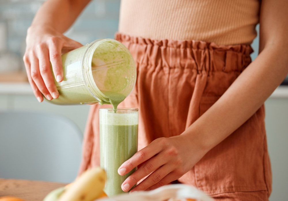 Person mixt Smoothie aus grünem Hafer
